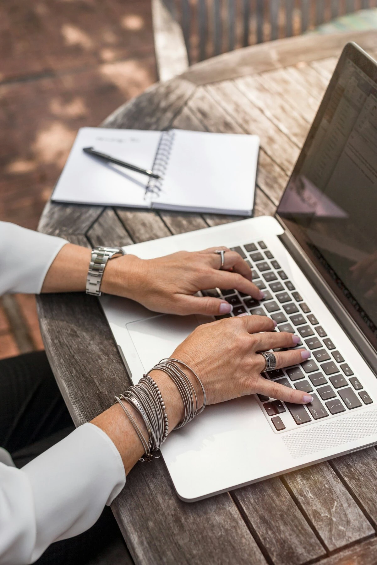 Hands typing on a laptop at an outdoor worktable